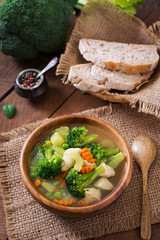 Chicken soup with broccoli, green peas, carrots and celery in  bowl on a wooden background in rustic style