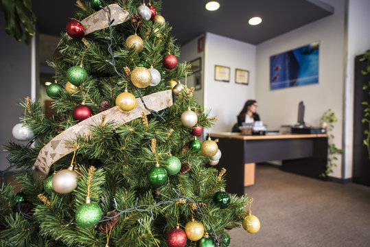 Decorated Christmas tree in office. Woman on background