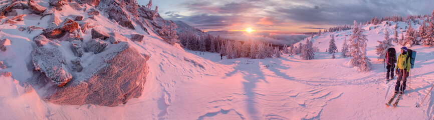 Skiers watching sunrise in winter mountains