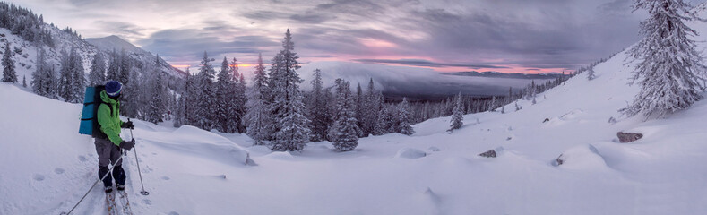 Skier watching sunrise in winter mountains