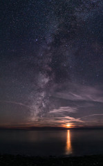 The Milky Way rising out of the sea, next to a setting Moon