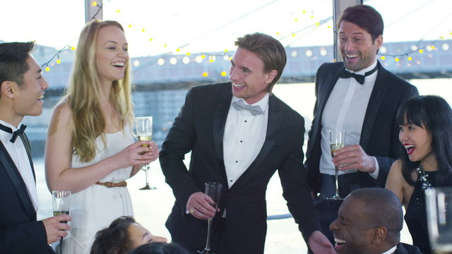 Attractive group of elegant friends drinking champagne at boat party