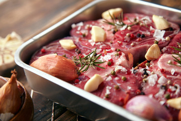 Closeup meat in steel pan with spices ready to cook on table