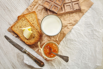 Top view of breakfast set with jam, bread, butter and milk