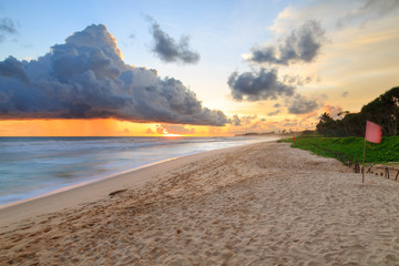 Sea  and beach with dark rain clouds at sunset