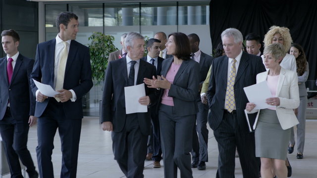  Large diverse business group talking as they walk through office building