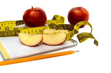 Apple, pencil and measuring tape on notepad isolated on white