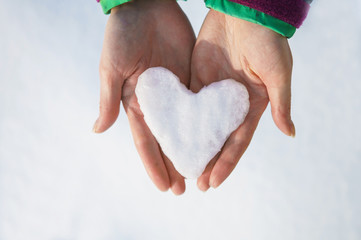Female hands holding snowball heart, Winter love background