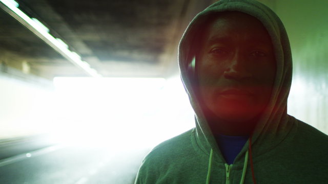  Portrait of athletic black male in a hooded sweatshirt, in urban environment. Could be an athlete in training or a suspicious character.