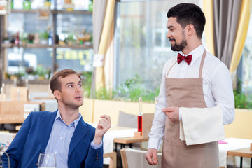 Cheerful male cafe worker is serving a customer