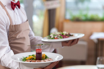 Skillful male cafe worker is serving customers