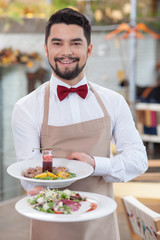 Handsome young waiter is working in restaurant