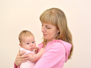 The young woman holds on hands of the baby. A family portrait on