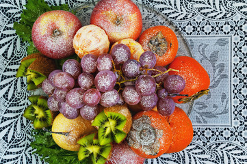 Fruits sprinkled with powdered sugar on a plate on a blue background