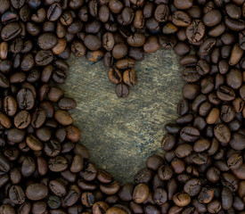 Heart shape made from coffee beans on wooden surface.
