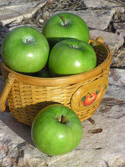 Basket of green apples on stone background