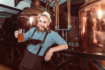 Happy smiling man with leather trousers (lederhose) tasting fresh brewed beer.