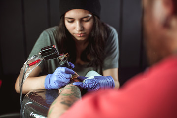 Obraz na płótnie Canvas Beautiful brunette girl makes tattoo. Tattooist makes a tattoo. Closeup