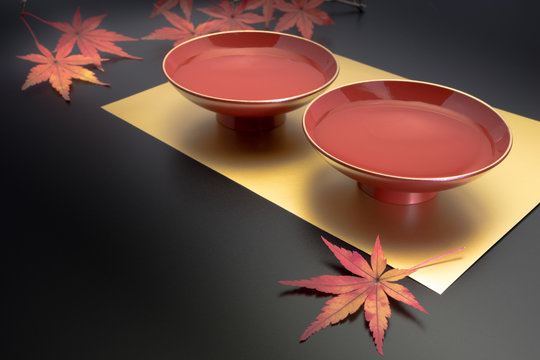 vermilion lacquer coated sake cups and maple leaves. vermilion sake cups are used for festive meals, especially for New Year celebration or wedding ceremonies.
