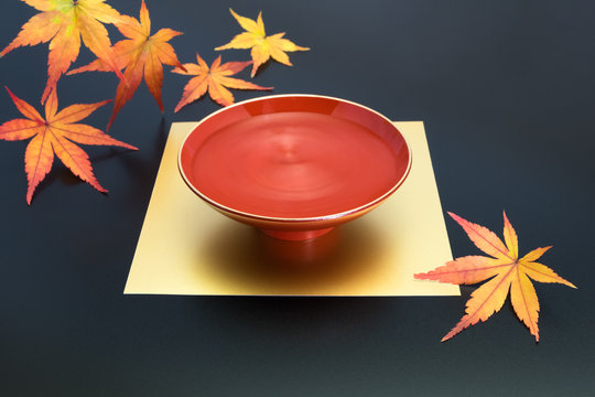 vermilion lacquer coated sake cup and maple leaves. vermilion sake cups are used for festive meals, especially for New Year celebration or wedding ceremonies.
