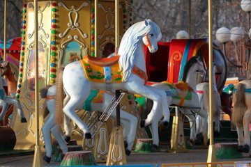 Fototapeta na wymiar Carousel with horses in City Park in morning sun