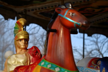 Gladiator in colorful carousel with horses