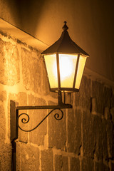 Traditional ancient street lamp on stone wall at night