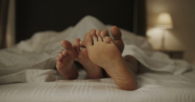  Happy feet of sexy couple in bed together. 