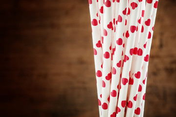 Background with white cocktail straws with red hearts, selective
