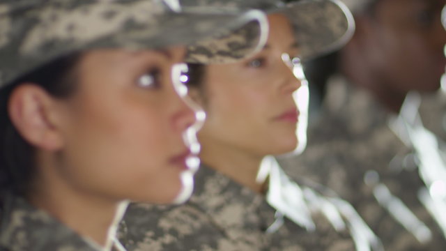  Close up on faces of mixed ethnicity female soldiers standing to attention. 