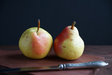 Two pears on a wooden board on a black background