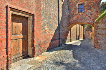 Cobbled street and red brick wall in italian town.