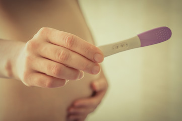 Pregnant woman holding a pregnancy test