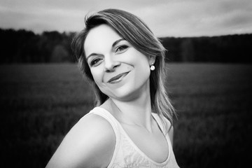 Black and white portrait of beautiful brunette on a meadow. She is wearing a sleeveless T-shirt. Fashion photography.