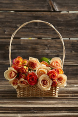 Fototapeta na wymiar Bouquet of orange roses in basket on brown wooden background
