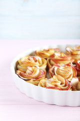 Fresh puff pastry with apple shaped roses on pink wooden table