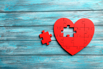 Red puzzle heart on blue wooden background