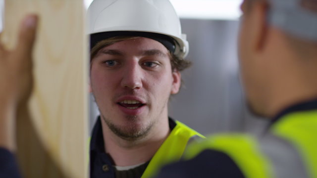  Male construction worker or tradesman working with male apprentice, showing him how to use a drill. 