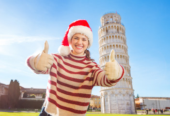 Obraz premium Woman in Santa hat showing thumbs up near Leaning Tour of Pisa