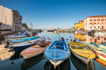Fototapeta na wymiar View of the Venetian Port of Piran, Slovenia with Boats in Foreground and Clear Blue Sky