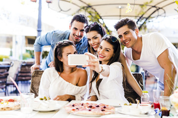 Group of young beautiful people sitting in a restaurant and taki