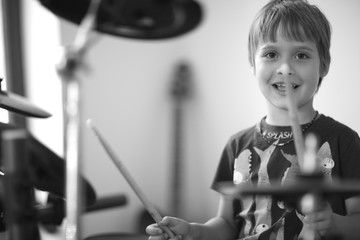 Closeup portrait of a cheerful small musician enjoying playing the drums