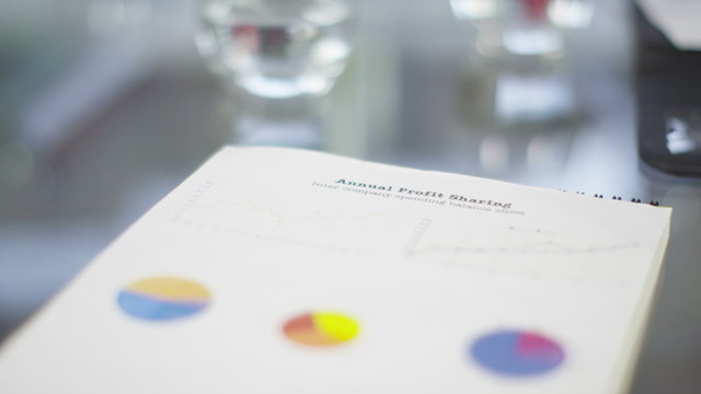  Close up on document with pie charts and business graphs on boardroom table. No people. 