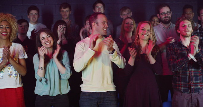  Young theatre audience give a standing ovation to the performers on stage