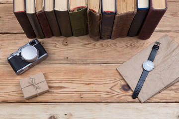 Top view on wooden desktop with books, camera, watch and gift bo
