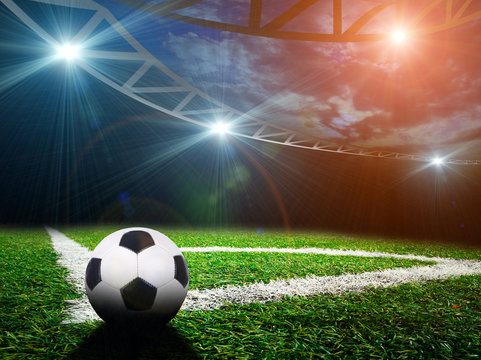 Soccer ball on green stadium, arena in night illuminated