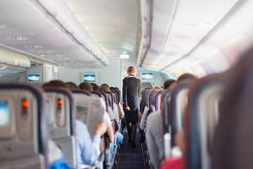 Fototapeta premium Stewardess and passengers on commercial airplane.