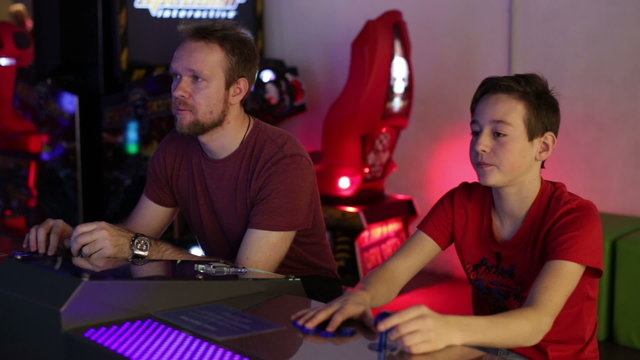 Man and teen playing on slot machine simulator