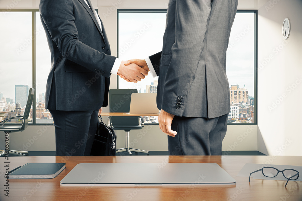 Sticker work space with laptop and businessmen shaking hands in modern o