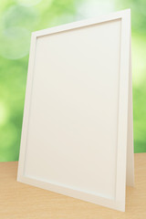 Blank white picture frame on wooden table, mock up